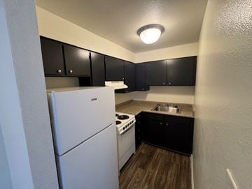 Las Vegas apartment for rent - A small kitchen with black cabinets and a white refrigerator.
