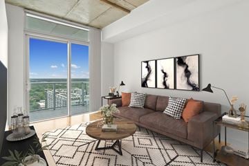 Orlando apartment for rent - A living room with a brown couch and a large window overlooking a cityscape.