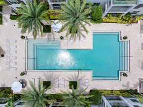 Jupiter apartment for rent - A swimming pool surrounded by palm trees and a building.