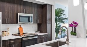 Jupiter apartment for rent - A modern kitchen with dark wood cabinets and a white countertop.