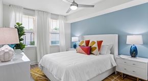 Jupiter apartment for rent - A bedroom with a white bed, a white nightstand, and a ceiling fan.