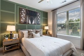 Midlothian apartment for rent - A bedroom with a large bed, a nightstand with a lamp, and a picture of a bridge on the wall.