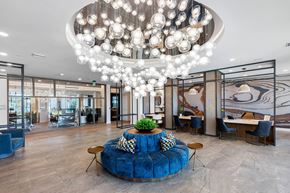 Orlando apartment for rent - A large, modern chandelier hangs above a blue, round sofa in a spacious, well-lit room.