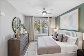 Wesley Chapel apartment for rent - A bedroom with a large bed, a dresser, and a ceiling fan.