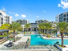 Orlando apartment for rent - A pool surrounded by palm trees and a building in the background.