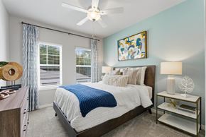 Wesley Chapel apartment for rent - A bedroom with a bed, a ceiling fan, and a nightstand with a lamp.