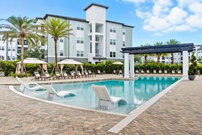 Wesley Chapel apartment for rent - A swimming pool with sun loungers and a building in the background.