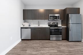 Concord apartment for rent - Designer kitchen featuring contemporary cabinetry, stainless steel appliances, quartz countertops, and an open-concept layout at NOVI Concord.
