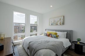 Bound Brook apartment for rent - Modern bedroom at The Rail Bound Brook with three large windows, city views, and a cozy bed—offering comfort and elegance in NJ apartment living.