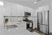 Wharton apartment for rent - A modern kitchen with a stainless steel refrigerator and a granite countertop. at 10 N. Main Apartments, New Jersey