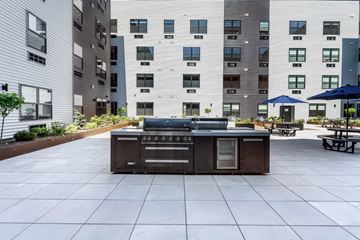 Newark apartment for rent - A BBQ grill is in the middle of a courtyard surrounded by buildings.