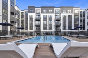 Teaneck apartment for rent - A modern apartment complex with a pool in the foreground.