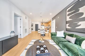 Teaneck apartment for rent - A modern living room with a green sofa and a wooden coffee table.
