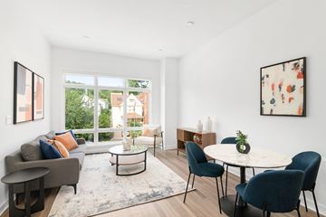 Montclair apartment for rent - A living room with a grey couch, a white coffee table, and a round table with chairs.
