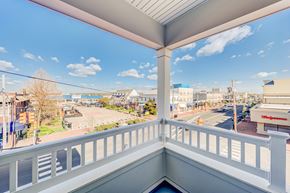 Belmar apartment for rent - A balcony overlooks a street with buildings and a clear sky.