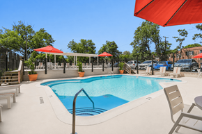 Arlington apartment for rent - A large outdoor swimming pool with red umbrellas and lounge chairs.