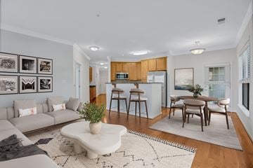 Lorton apartment for rent - A modern living room with a grey sofa, a coffee table, and a dining table set up.