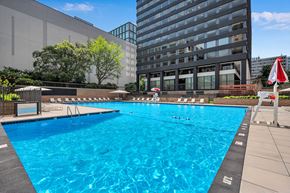 Arlington apartment for rent - A large blue swimming pool in front of a building.