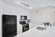 Arlington apartment for rent - A black refrigerator is on the left in a white kitchen.