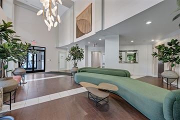 Arlington apartment for rent - A modern living room with a long green couch and a wooden beam on the wall.