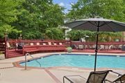 Woodbridge apartment for rent - A pool with a red bench and a black umbrella.