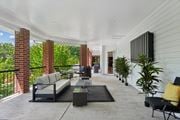 Woodbridge apartment for rent - A patio with a black couch and a black chair with a yellow pillow.