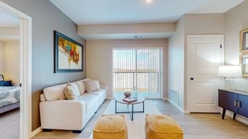 Lakeville apartment for rent - A living room with a white couch, a yellow ottoman, and a painting on the wall.