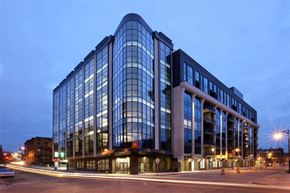 Grand Rapids apartment for rent - A modern glass building is illuminated at dusk.