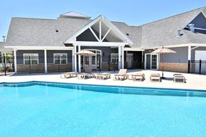 Holt apartment for rent - a large swimming pool in front of a building with chairs and umbrellas