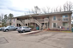 East Lansing townhouse for rent - A two-story apartment building with a parking lot in front.