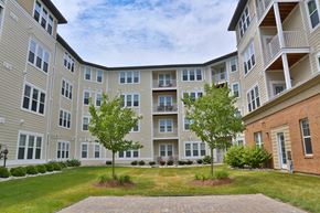 Auburn Hills apartment for rent - an exterior view of an apartment building with grass and trees
