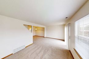 Lansing townhouse for rent - A spacious room with a carpeted floor and a window with blinds.