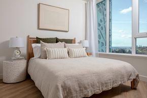 Coquitlam apartment for rent - A bedroom with a large bed, a nightstand with a lamp, and a framed picture on the wall.