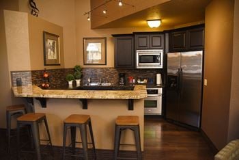 A kitchen with a granite countertop and bar stools.