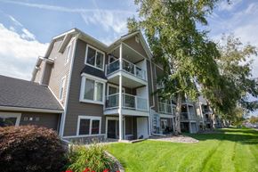 Spokane apartment for rent - A large apartment building with a balcony and a tree in front.