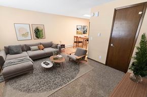 Spokane apartment for rent - A living room with a grey sofa, a coffee table, and a wooden door.