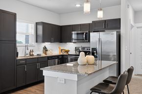 Fort Worth apartment for rent - A modern kitchen with a granite countertop and black cabinets.