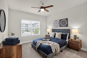 Fort Worth apartment for rent - A bedroom with a large bed, a ceiling fan, and a window with a view of a cityscape.