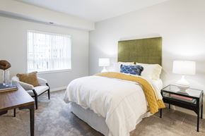 Ramsey apartment for rent - A bedroom with a white bed and a yellow throw.