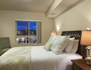 Spokane apartment for rent - A bedroom with a bed, a chair, and a window overlooking a street.