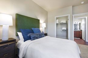 Round Rock apartment for rent - A bedroom with a bed, nightstand, and a green headboard.