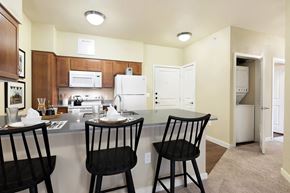Austin apartment for rent - A kitchen with a white refrigerator, brown cabinets, and a table with three chairs.
