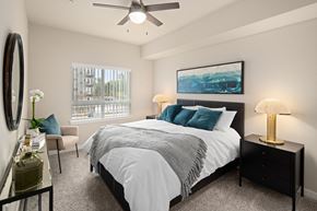Burlington apartment for rent - A bedroom with a large bed, a ceiling fan, and a painting on the wall.