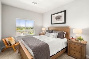 Austin apartment for rent - A bedroom with a large bed, a chair, and a window overlooking a balcony.