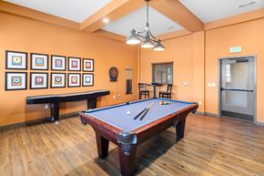 Austin apartment for rent - A pool table in a room with orange walls and a bench.