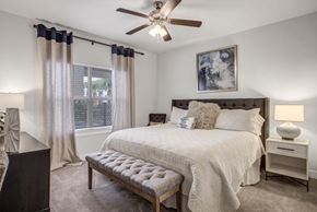 Cedar Park apartment for rent - A bedroom with a bed, nightstand, and a ceiling fan.
