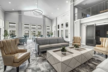 Fort Worth apartment for rent - A modern living room with a grey sofa, a brown leather chair and a white coffee table.