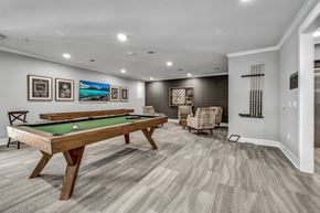 Fort Worth apartment for rent - A pool table is in the middle of a room with a chair and pictures on the wall.