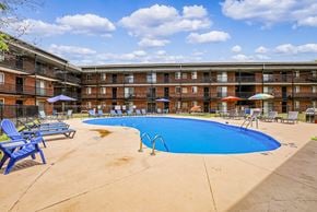 Columbus apartment for rent - A large swimming pool in front of a red brick building.