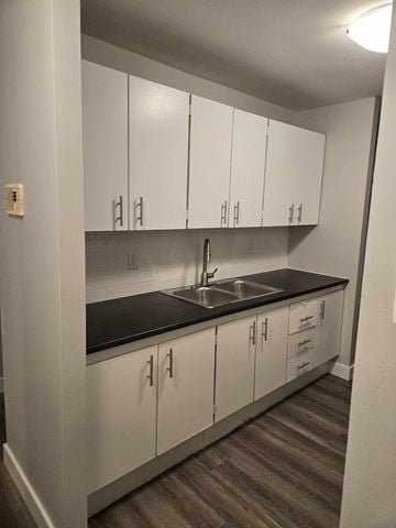 Bedford apartment for rent - a kitchen with white cabinets and a sink